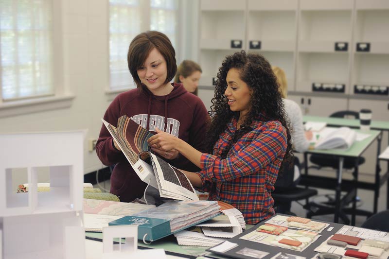 Two interior design students flipping through swatches.